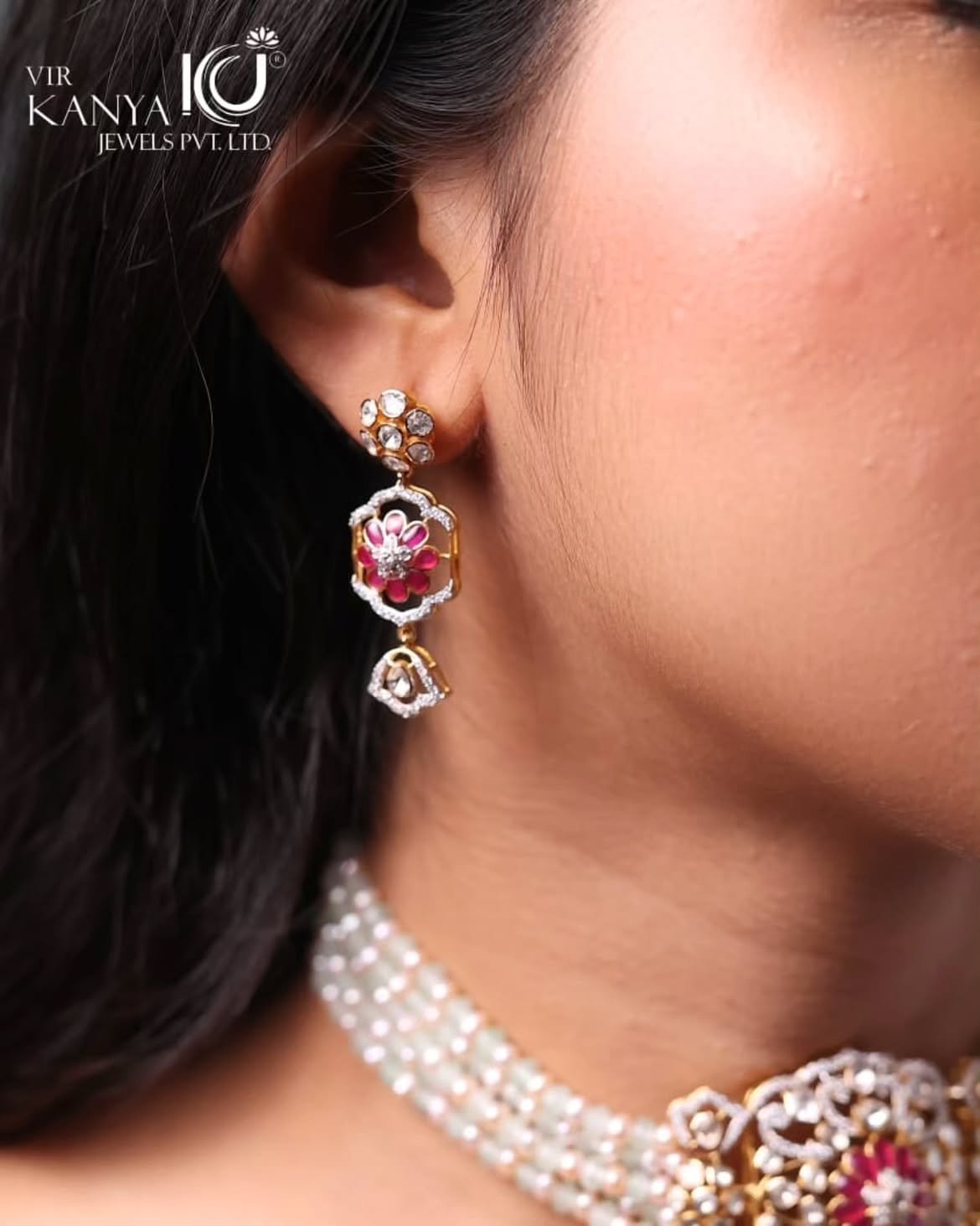A polki and ruby drop earring worn above a pearl choker